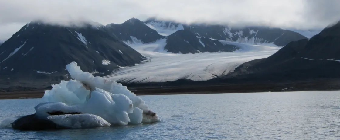 Iceberg floating in foreground, glacier in background