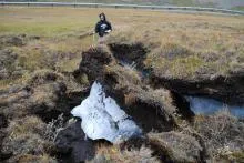 A researcher slakes his thirst with ice chopped from an exposed ice layer